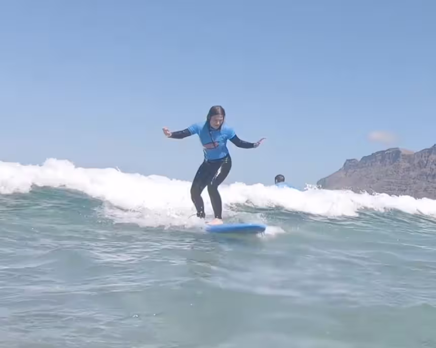 A girl ridig a green wave, with a nice upright longboard styel ona sunny day with nice small to mid sized waves.