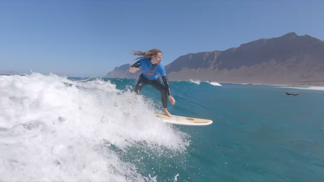 A young woman riding a head-high wave, right after taking off.