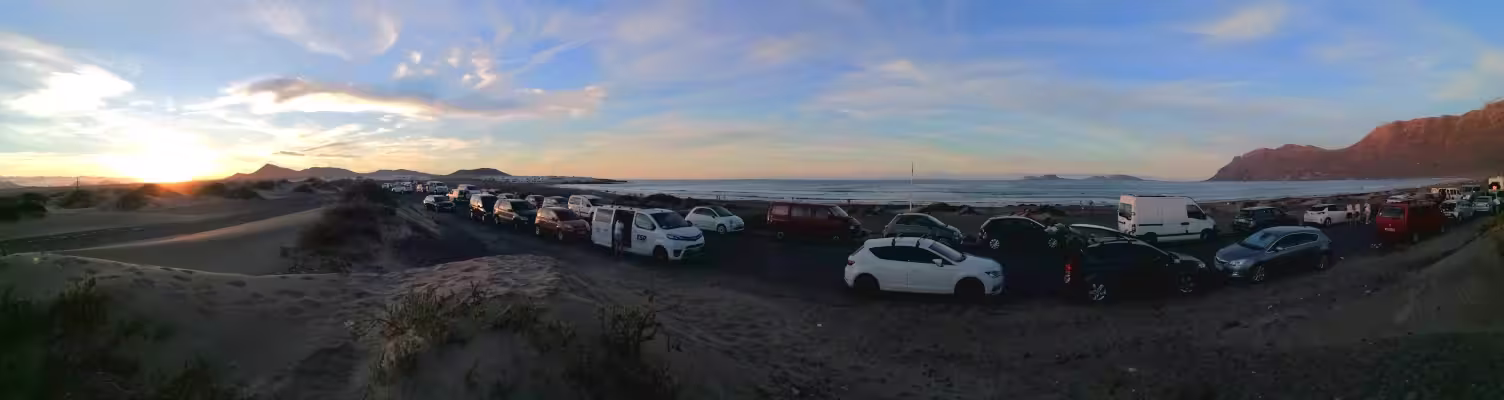 The road next to the beach at sunset. Panoramic view with dunes, beach and and th eisland of La Graciosa ath the horizon.